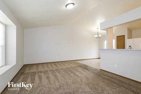 a spacious living room with carpet and white walls