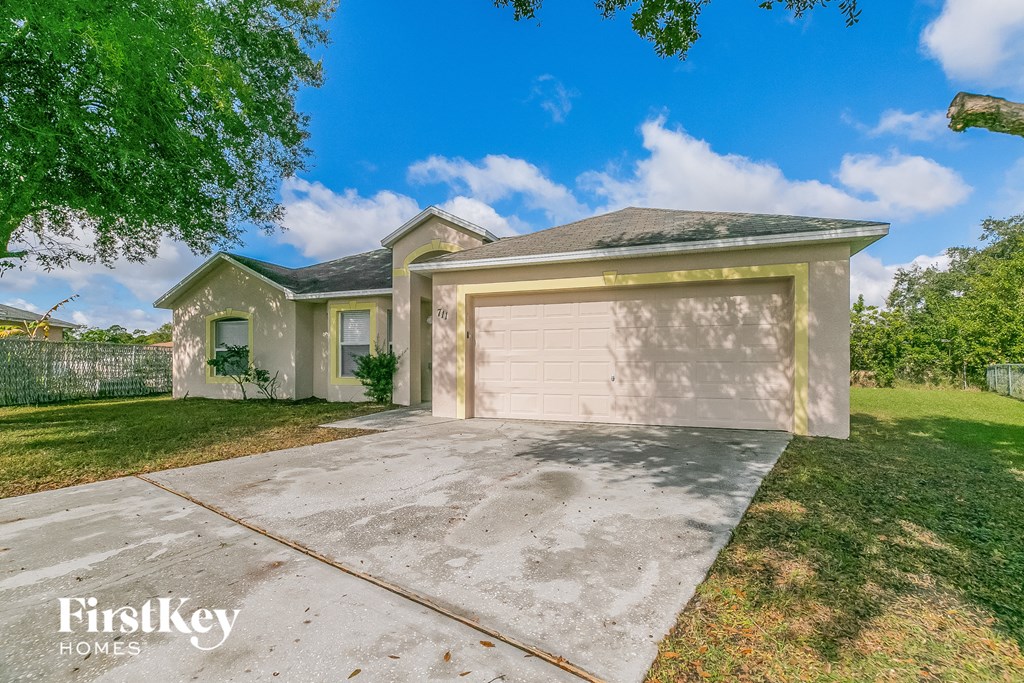 a beige house with a garage with a concrete driveway