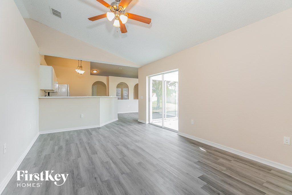 a spacious living room with a ceiling fan and a kitchen