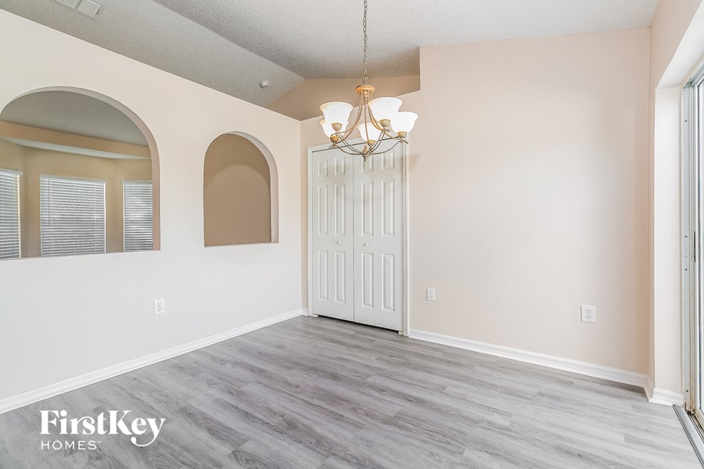 an empty living room with a white door and a chandelier