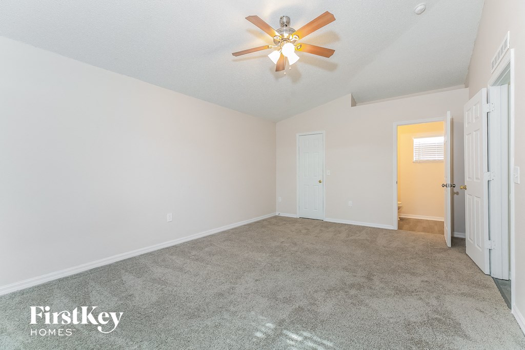a spacious living room with carpet and a ceiling fan