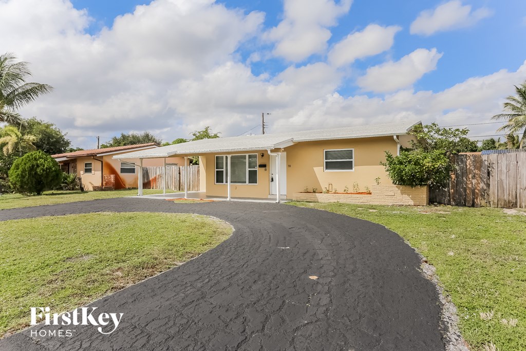 a home with a driveway and a yellow house with a black road