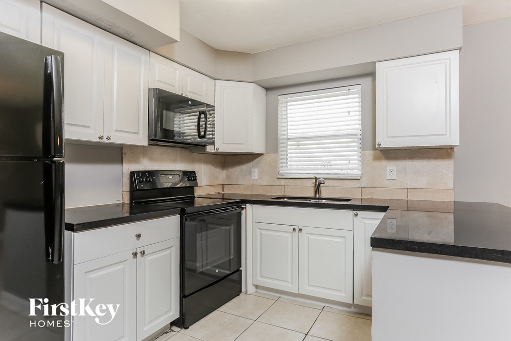 a white kitchen with black appliances and white cabinets