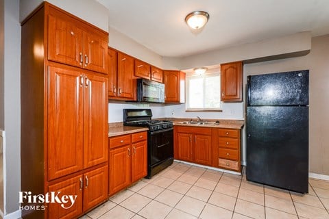 A kitchen with wooden cabinets and a black refrigerator.