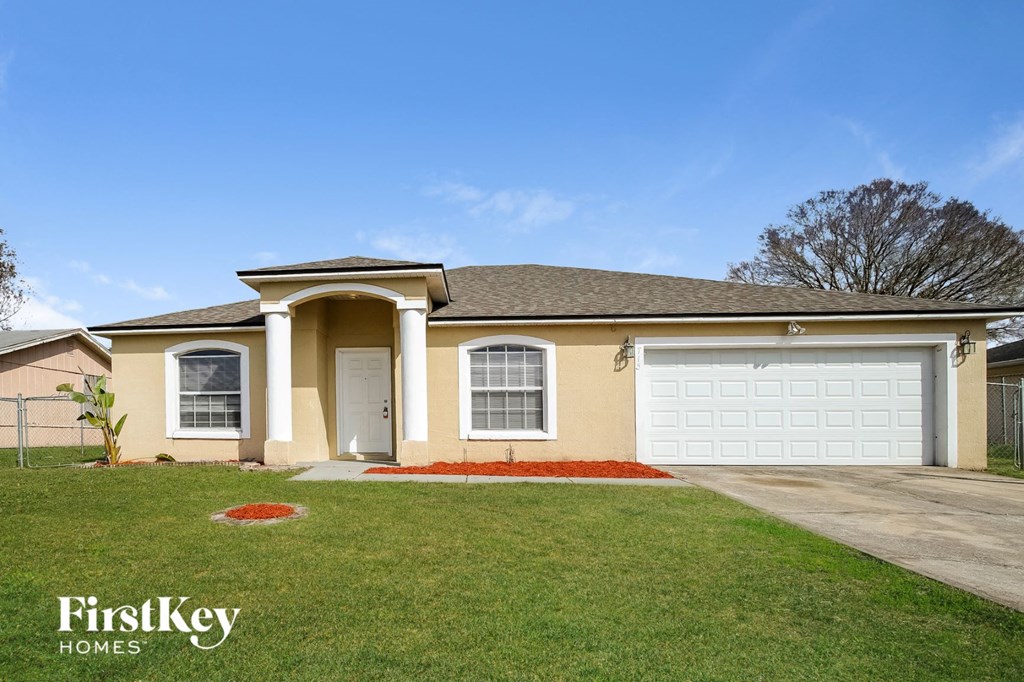 a beige house with a garage and a lawn