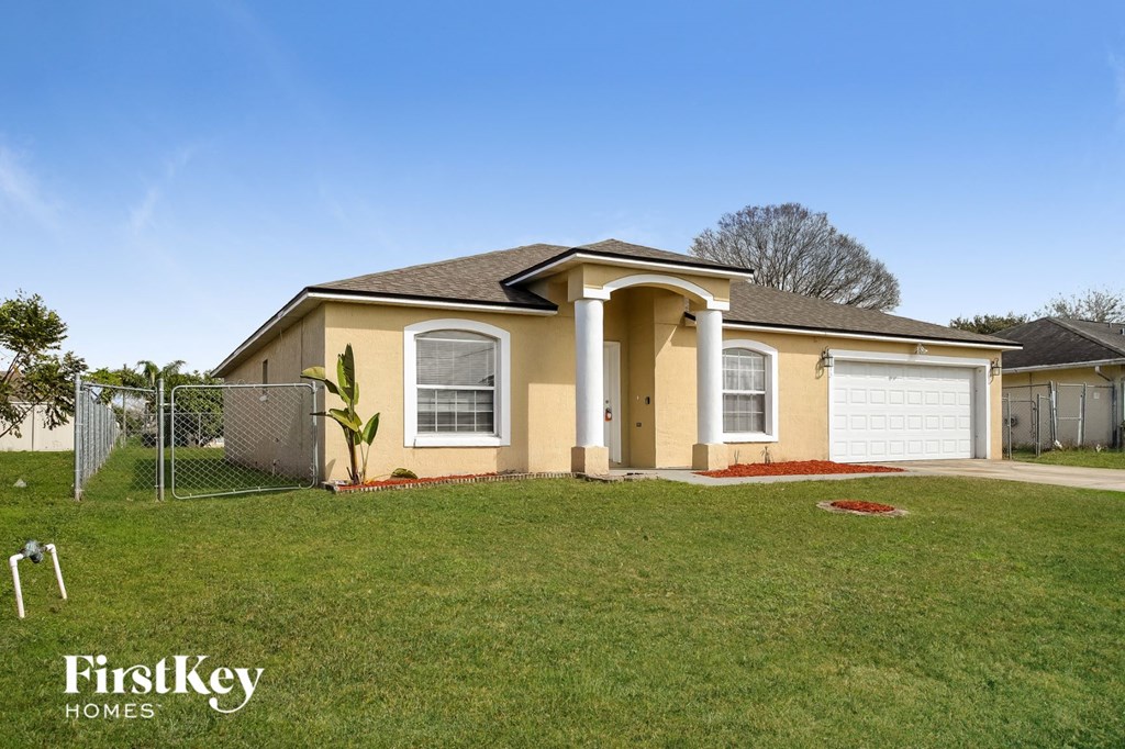a yellow house with a yard and a chain link fence