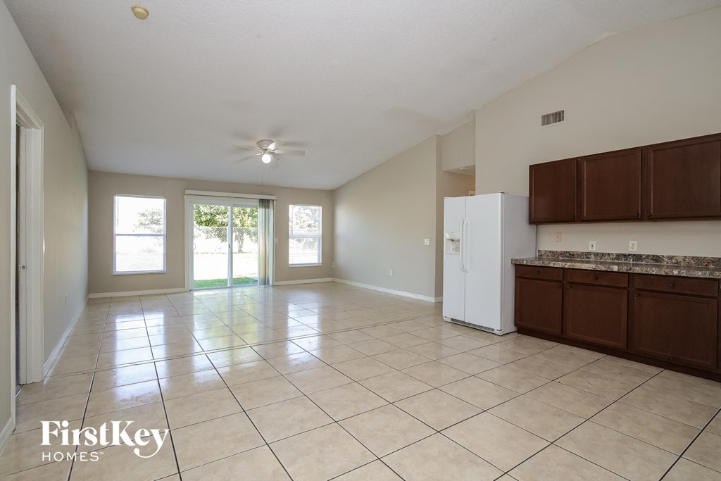 an empty kitchen and living room with a refrigerator and cabinets
