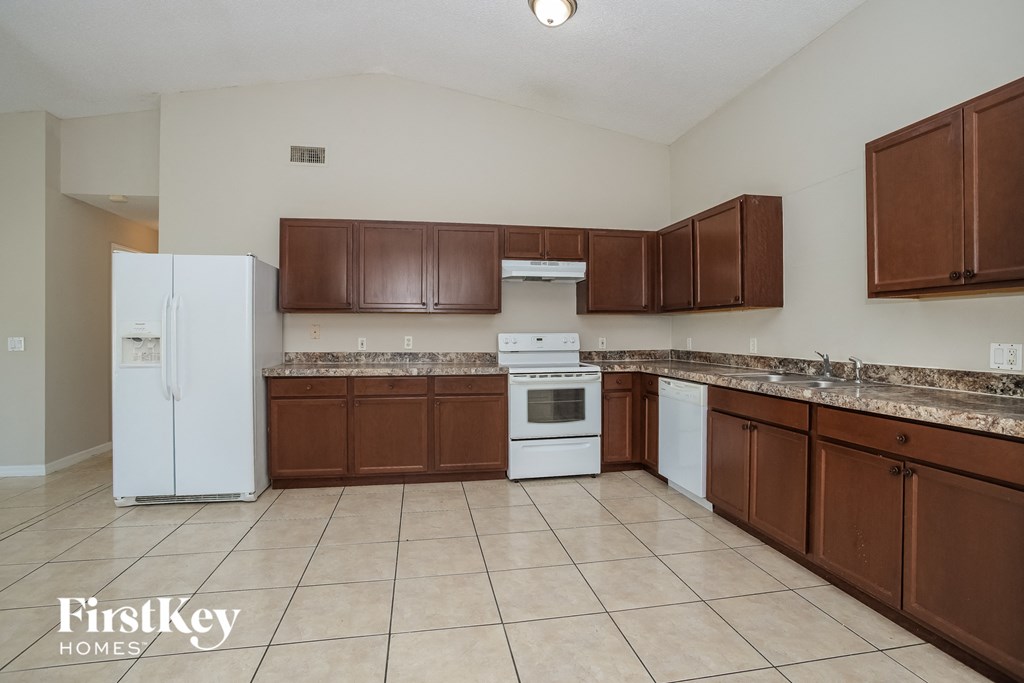 an empty kitchen with white appliances and wooden cabinets