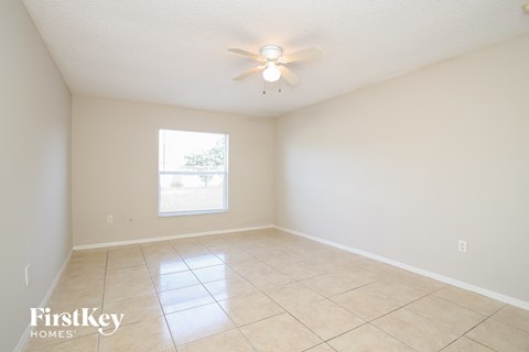 a spacious living room with tiled flooring and a ceiling fan