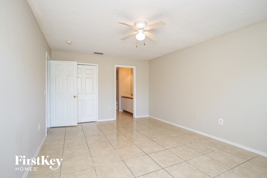 a spacious living room with tile flooring and a ceiling fan