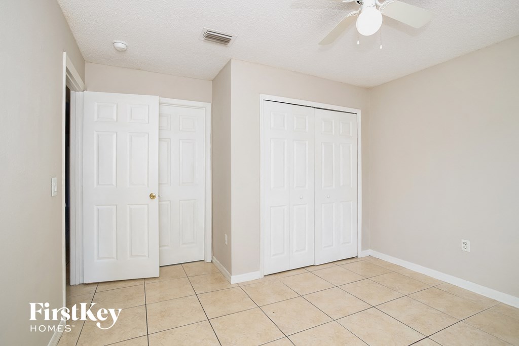 a room with two closets and a tile floor and a ceiling fan