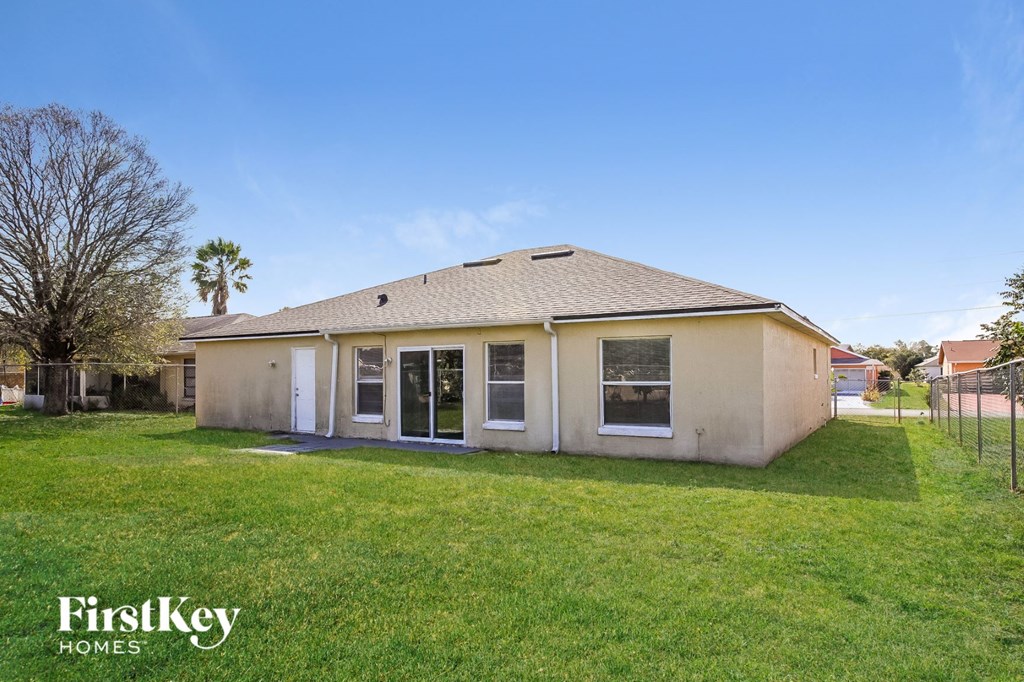 a small tan house with a yard and a fence