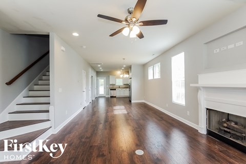 an empty living room with a ceiling fan and a fireplace