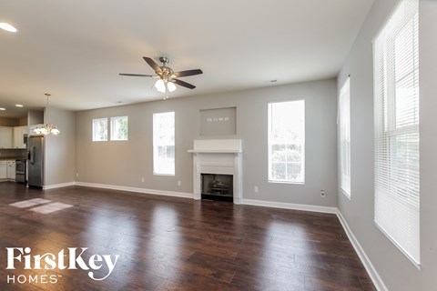 an empty living room with a ceiling fan and a fireplace