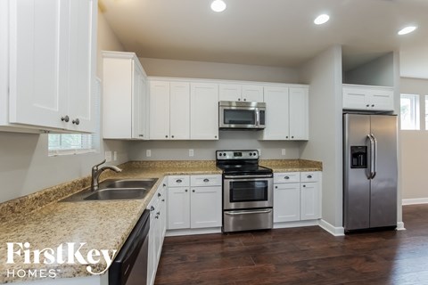 a kitchen with white cabinets and granite counter tops and stainless steel appliances