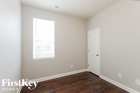a bedroom with a door and a window and a wooden floor