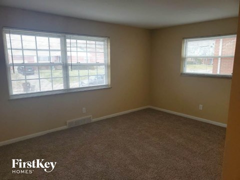 A room with a carpeted floor and two windows.