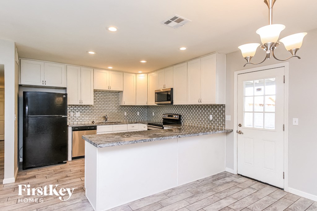 a kitchen with white cabinets and a black refrigerator