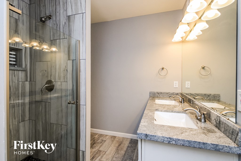 a bathroom with a sink and a shower and a mirror