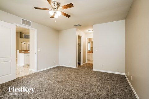 a spacious living room with carpet and a ceiling fan