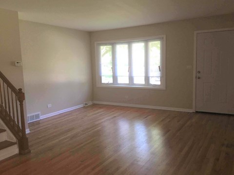 A room with wooden floors and a window with white blinds.