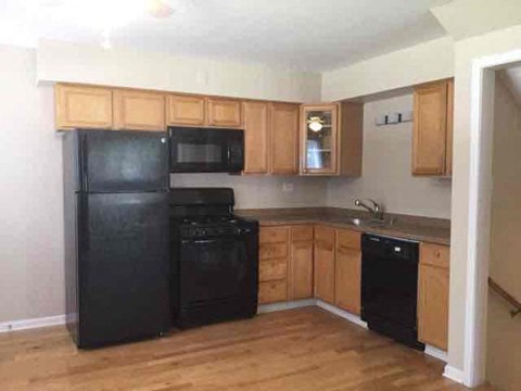 A kitchen with black appliances and wooden cabinets.