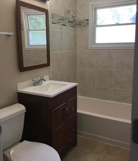 A bathroom with a toilet, sink, and a window.
