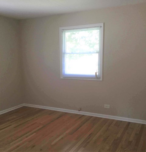 A room with a window and wooden flooring.