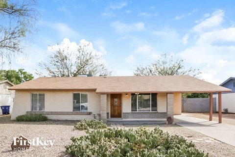 a small white house with a front porch and cacti