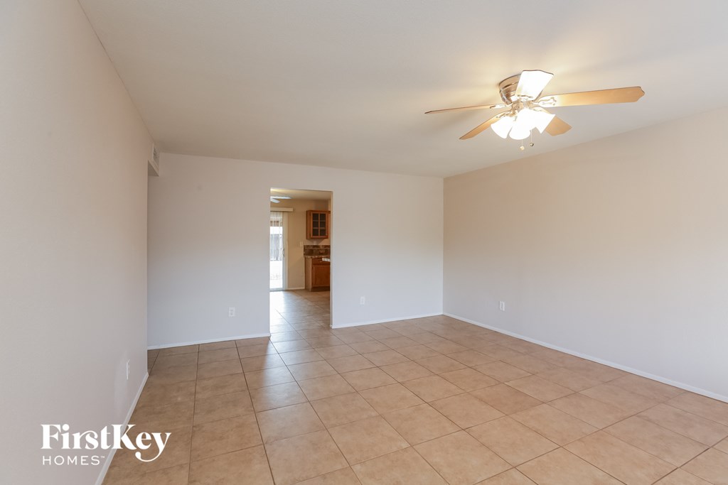 an empty living room with white walls and a ceiling fan
