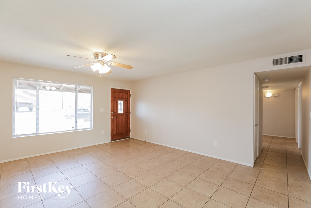 an empty living room with tile flooring and a ceiling fan