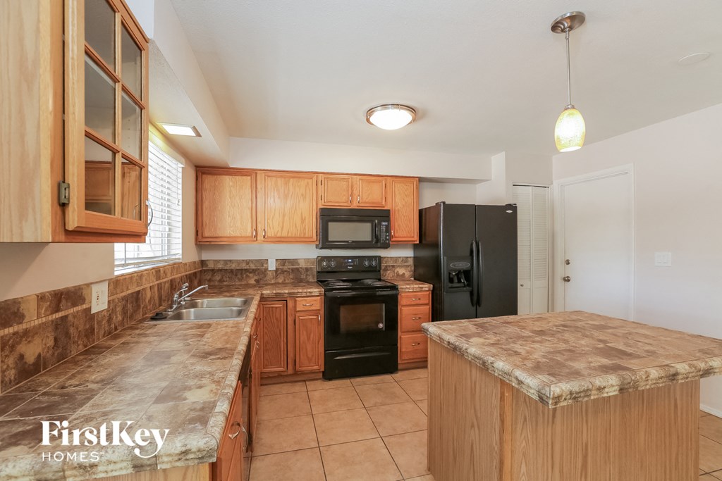 a kitchen with wooden cabinets and black appliances and granite counter tops