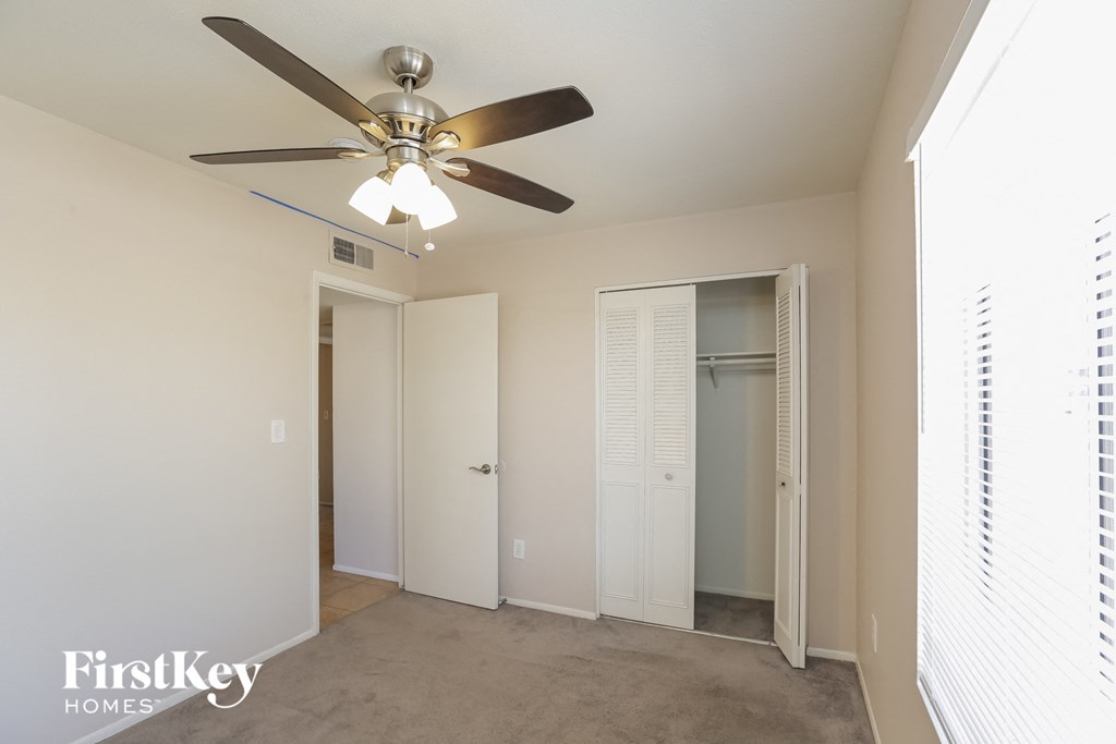 a bedroom with a ceiling fan and a closet