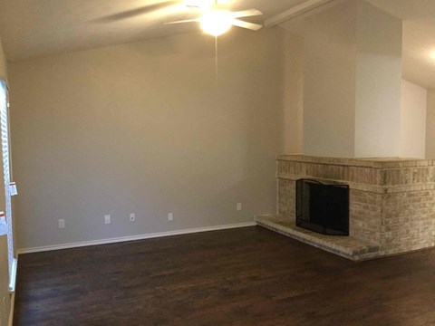A living room with a fireplace and a ceiling fan.