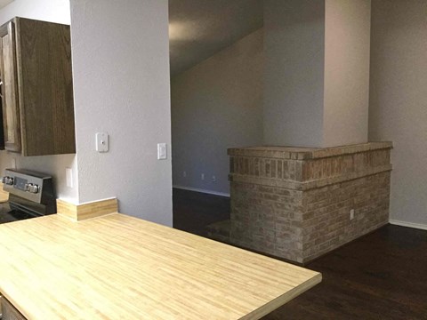 A kitchen with a wooden counter top and a brick wall.