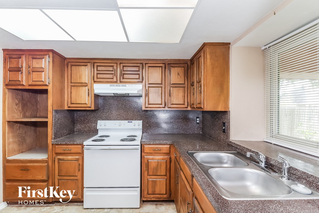 a kitchen with wooden cabinets and white appliances and a sink