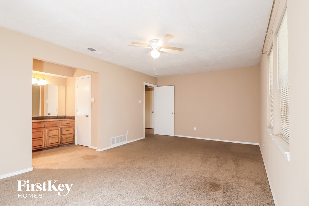 a spacious living room with carpet and a ceiling fan