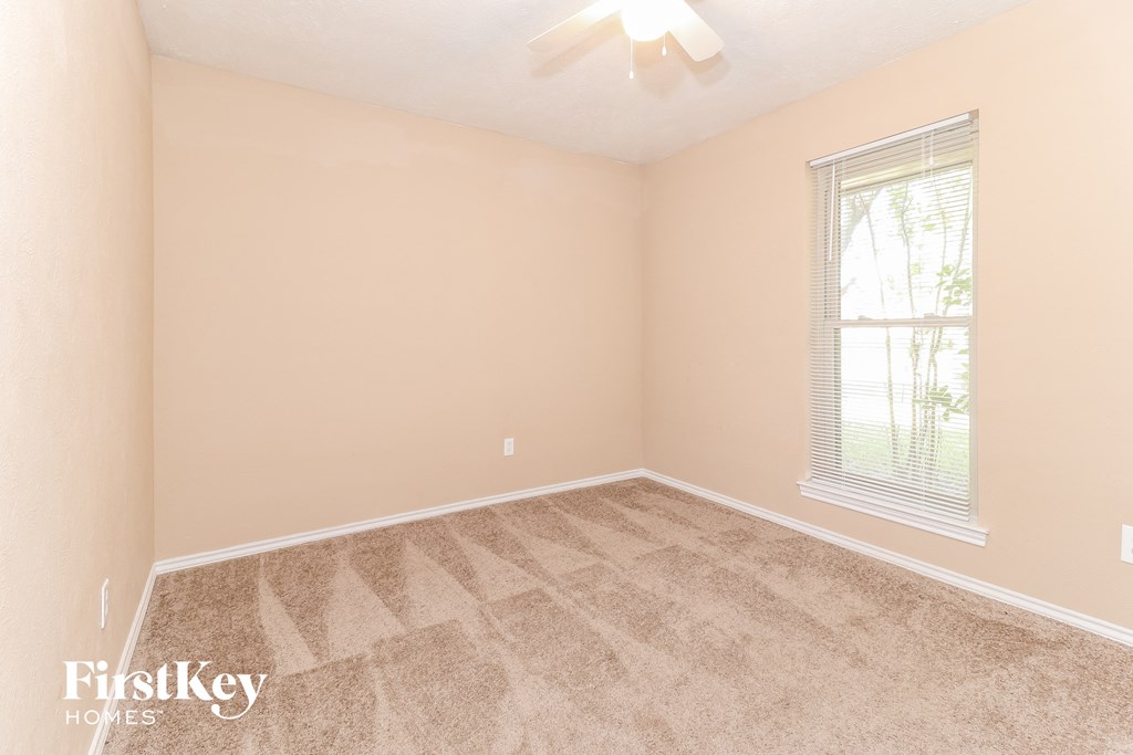 a bedroom with beige carpet and a window