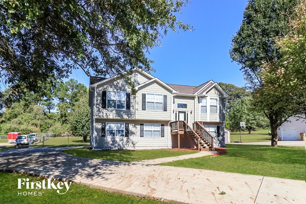 a white house with a driveway and trees in front of it
