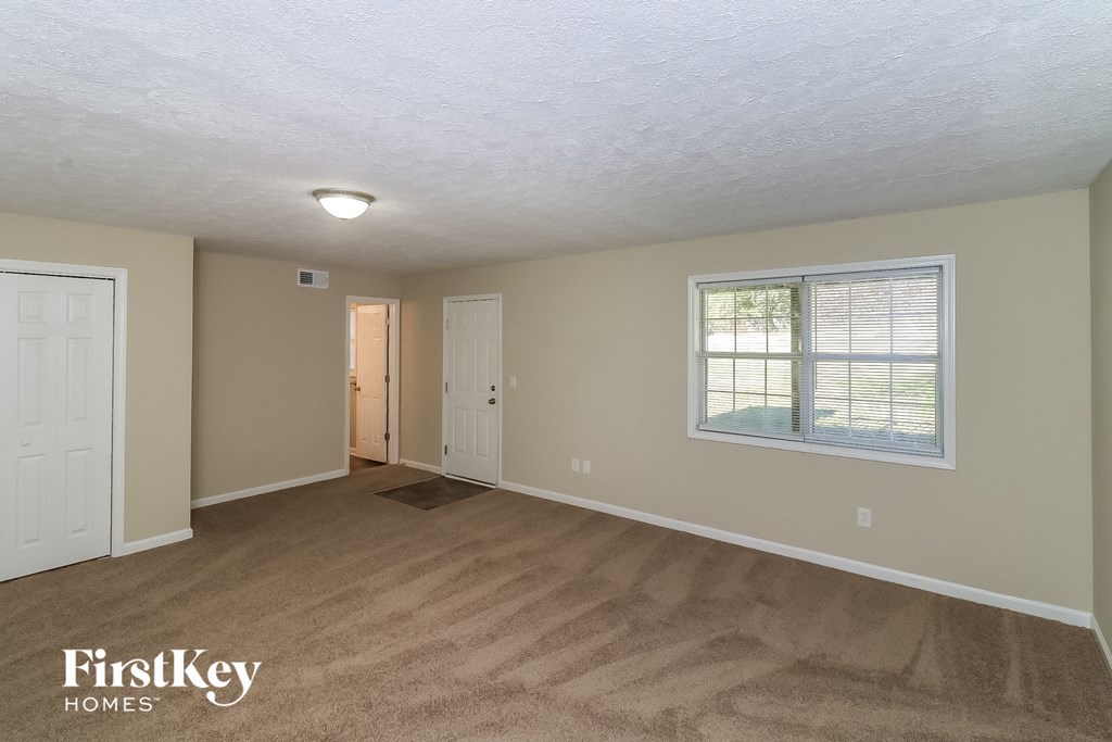 the living room of an empty house with a door and a window