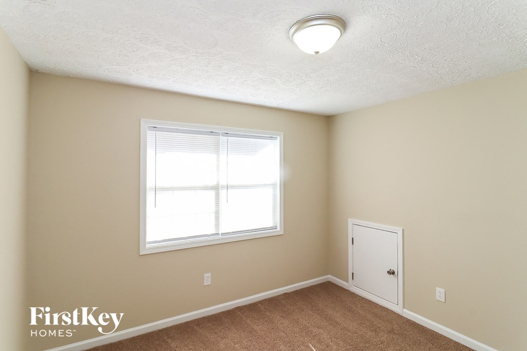 a bedroom with a window and a door and a carpeted floor