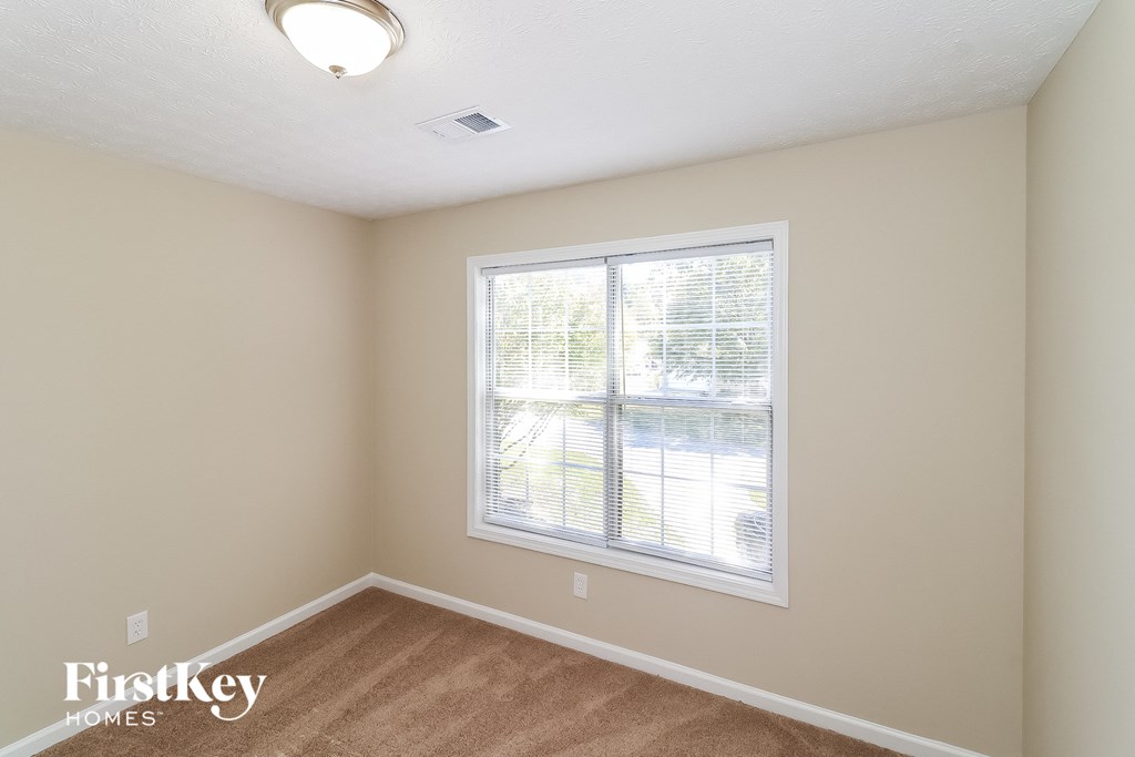 a bedroom with a large window and a carpeted floor