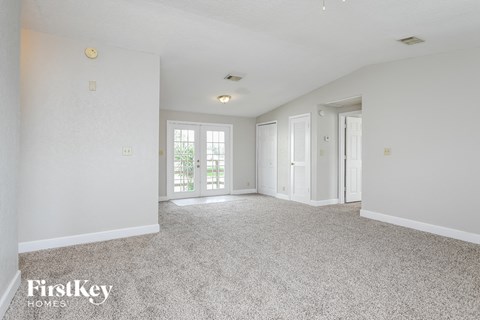 a spacious living room with white walls and white carpet