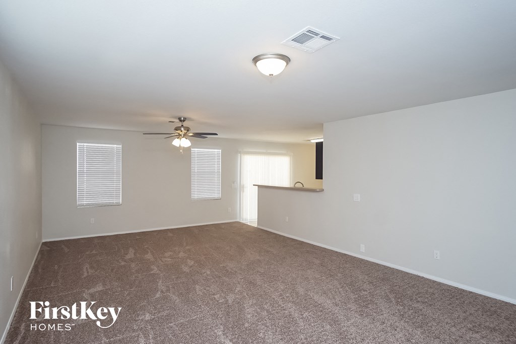 the living room of an empty house with a ceiling fan