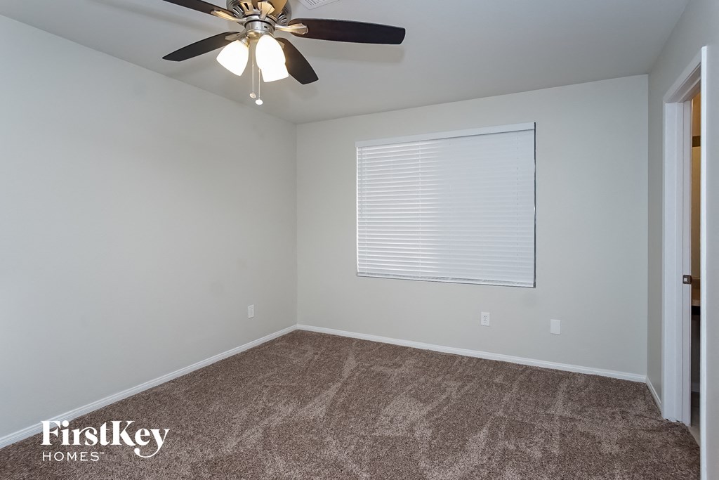 the bedroom has a carpeted floor and a ceiling fan