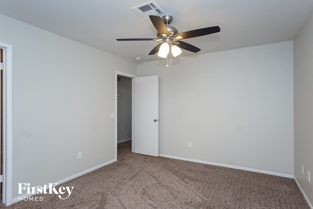 a bedroom with white walls and a ceiling fan