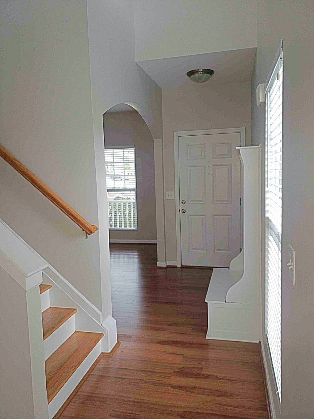 A hallway with a white door and wooden stairs.