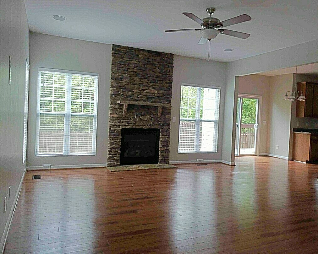 A living room with a fireplace and a ceiling fan.