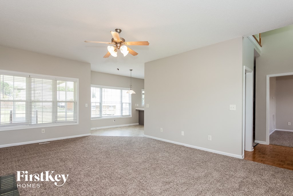 the living room and dining room of an empty house with a ceiling fan