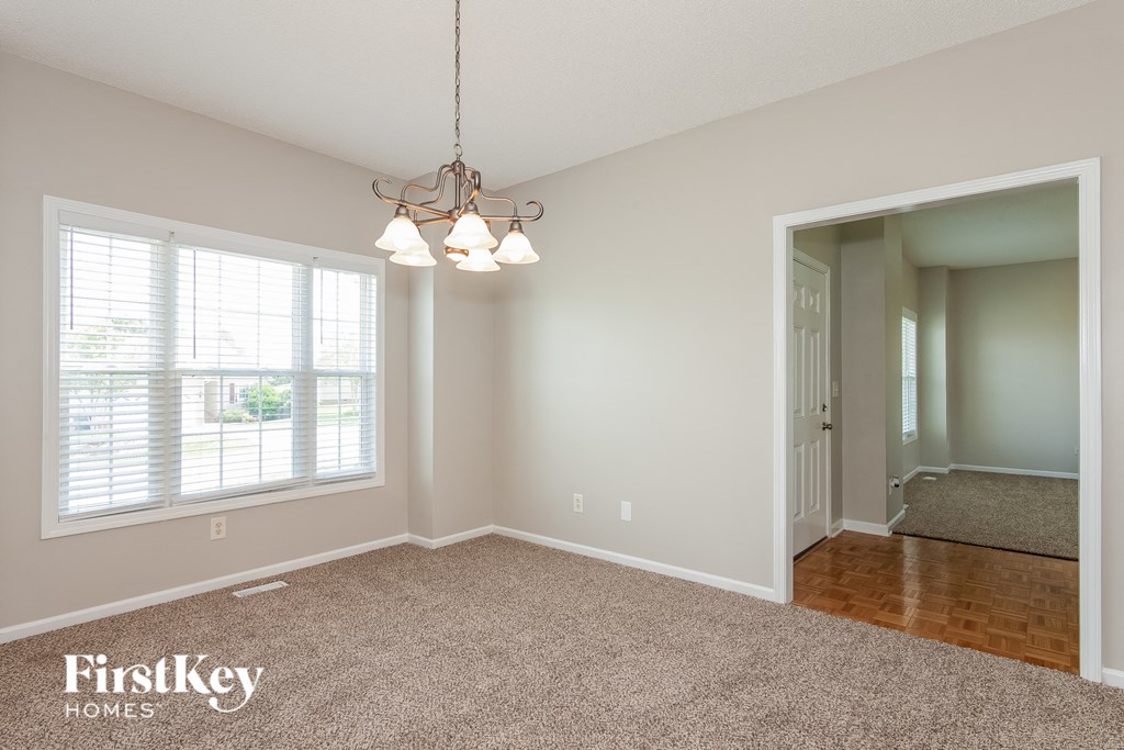 an empty dining room with a chandelier and a window